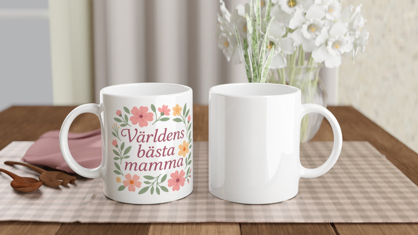 Mugg med texten Världens bästa mamma omgiven av mjuka blommor och blad i pastellfärger.