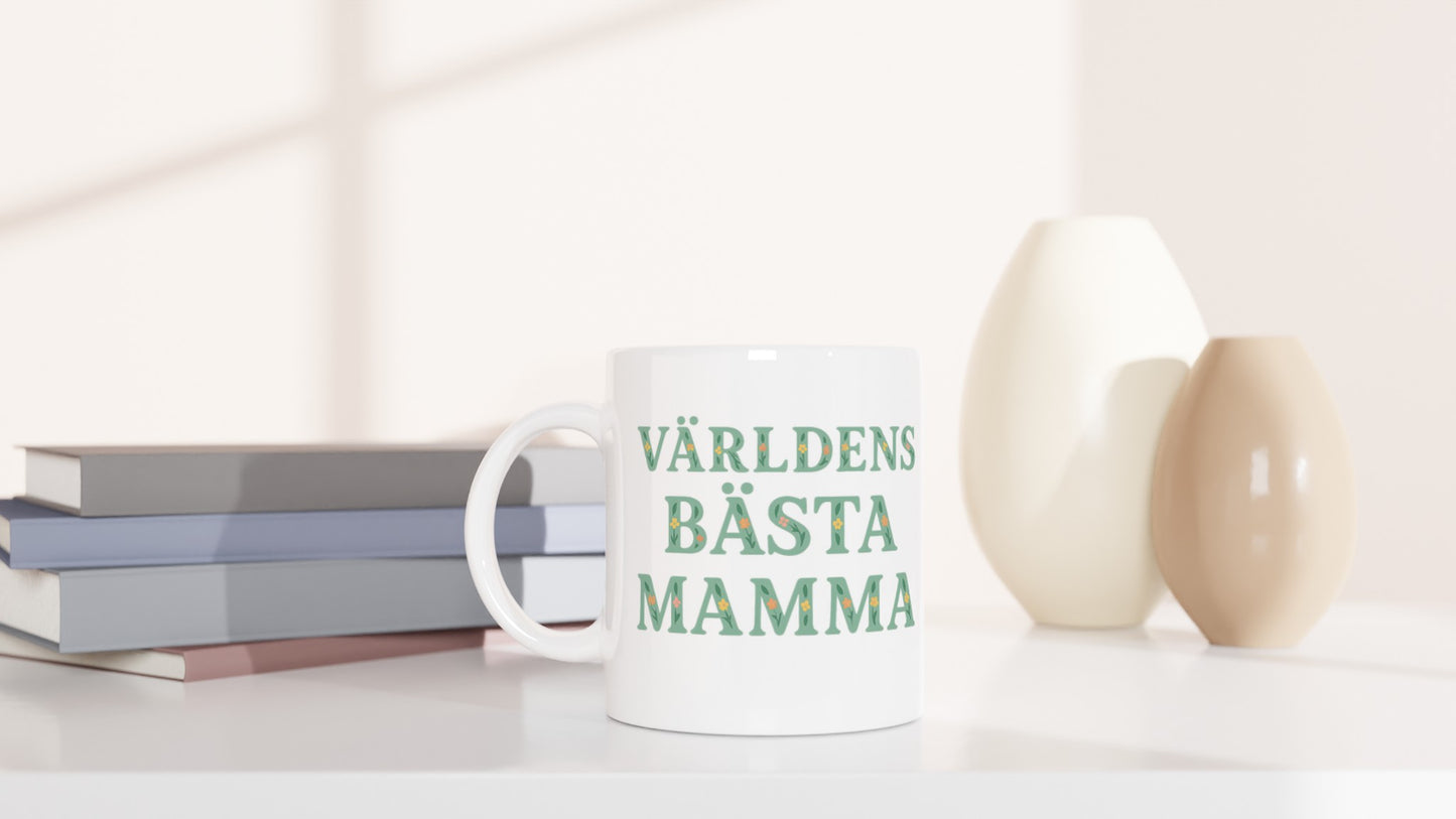 Mugg med blommigt mönster och texten 'Världens bästa mamma' i mjuk grön färg. Perfekt present till mamma.