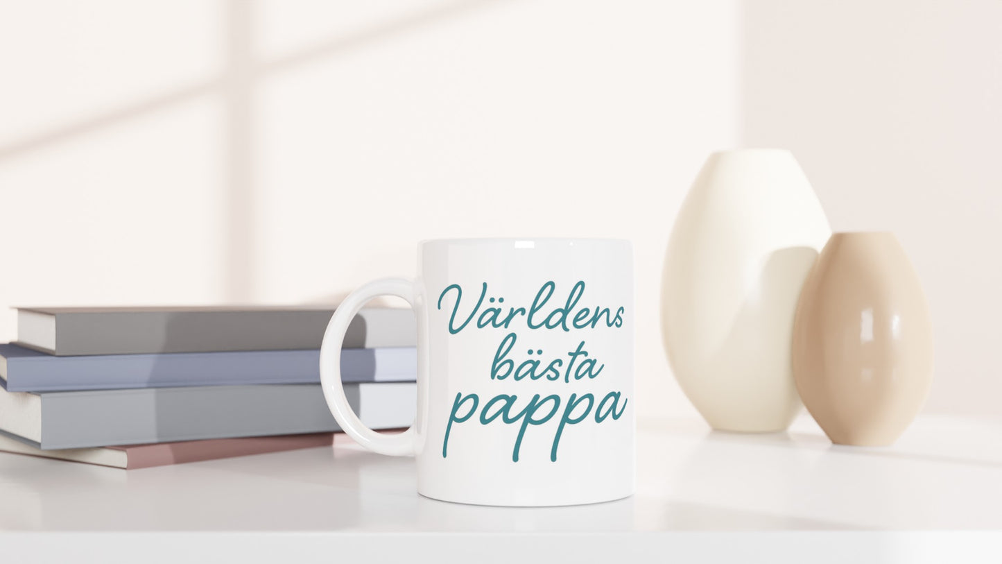 Mugg med texten 'Världens bästa pappa' i elegant handskriven font och varm blågrön färg. Perfekt till fars dag eller som uppskattning.