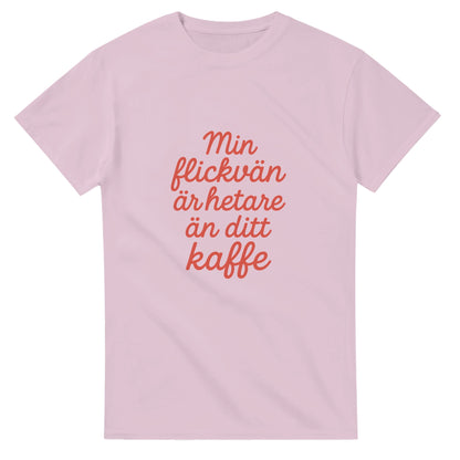 T-shirt med texten 'Min flickvän är hetare än ditt kaffe' i röd skrivstil. Perfekt för att visa kärlek med en touch av humor.