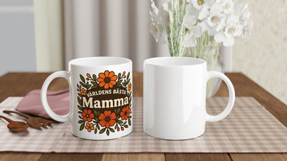 Mugg med blomstrande mönster och texten 'Världens bästa mamma' i fokus, omgiven av varma blommor. För att hedra mamman.